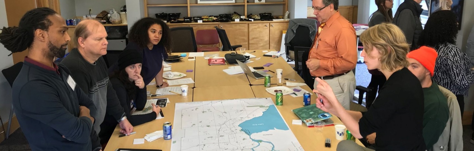 A group of urban planning faculty and students and community members from Buffalo stand over a map discussing climate resilience strategies. 